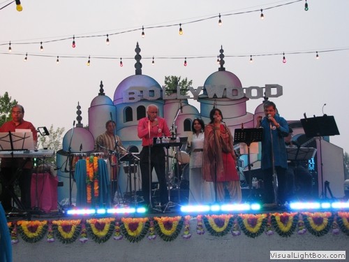 Performers on a stage with a Bollywood themed backdrop prop for rental.