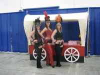 Three women standing in front of a wagon, posed.