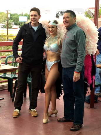 Two men and one woman with pink feathers posing for the picture.